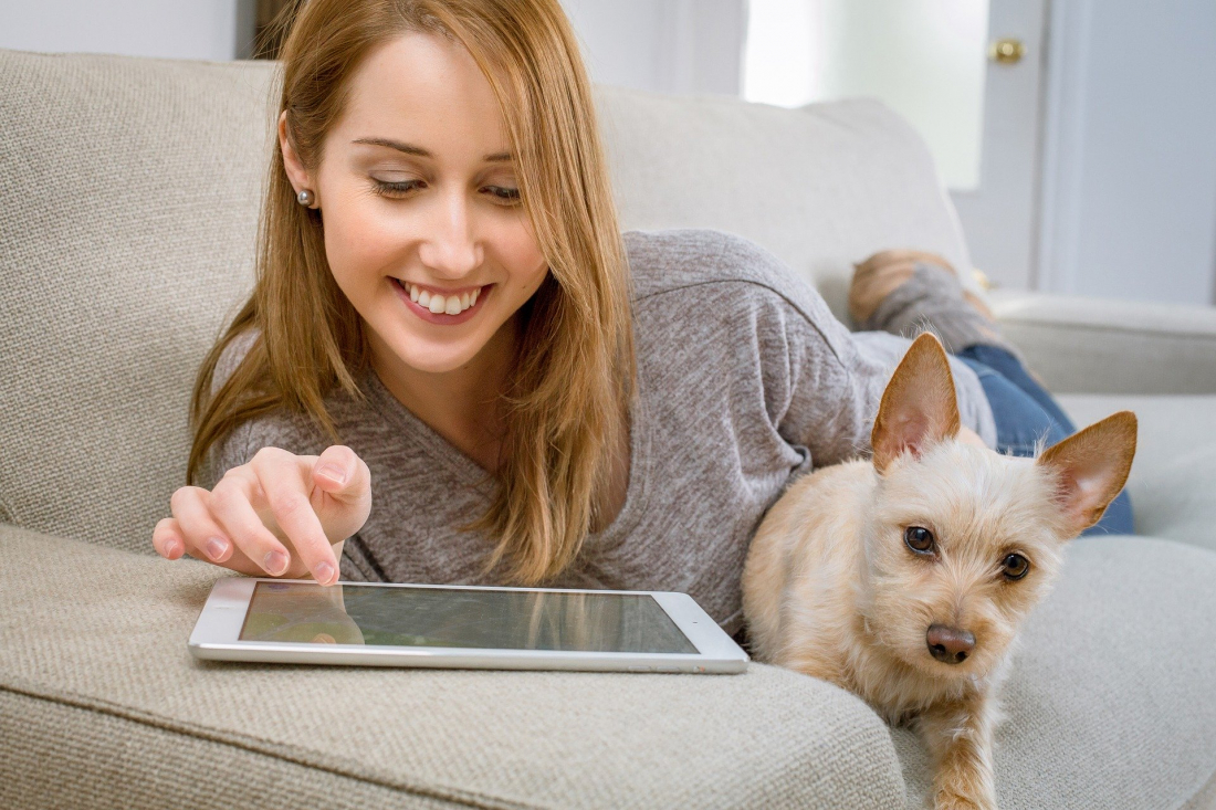 Corona-Aktion: Frau mit Tablet und Hund auf Sofa